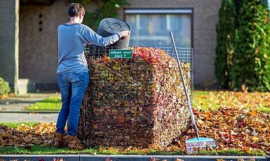 Foto van iemand die bladafval in een bladkorf gooit